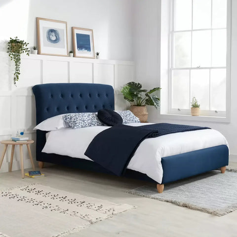 Bradley Bed: A chic and modern masterpiece in midnight blue fabric with a generously cushioned headboard. Sprung slatted base for ultimate comfort and impressive weight load capacity. Elevate your bedroom with luxury and sophistication - Lifestyle Image