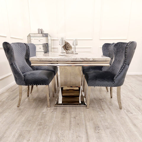 Image showcasing the Bentley Marble Dining Table Set with a Light Grey Marble Top, complemented by a Chrome U Shape Pedestal Base. The set includes Bentley Dining Chairs in Grey velvet, featuring a buttoned back design, Chrome Lion Knocker, and high-quality chrome legs, creating a luxurious and stylish dining ensemble. - 004