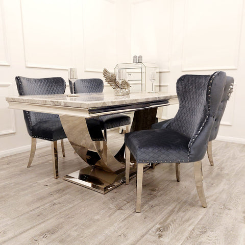 Image showcasing the Bentley Marble Dining Table Set with a Light Grey Marble Top, complemented by a Chrome U Shape Pedestal Base. The set includes Bentley Dining Chairs in Grey velvet, featuring a buttoned back design, Chrome Lion Knocker, and high-quality chrome legs, creating a luxurious and stylish dining ensemble. - 005