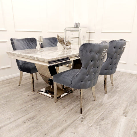 Image showcasing the Bentley Marble Dining Table Set with a Light Grey Marble Top, complemented by a Chrome U Shape Pedestal Base. The set includes Bentley Dining Chairs in Grey velvet, featuring a buttoned back design, Chrome Lion Knocker, and high-quality chrome legs, creating a luxurious and stylish dining ensemble. - 006