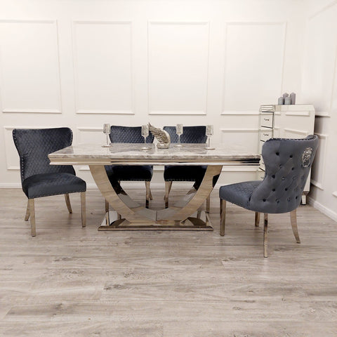 Image showcasing the Bentley Marble Dining Table Set with a Light Grey Marble Top, complemented by a Chrome U Shape Pedestal Base. The set includes Bentley Dining Chairs in Grey velvet, featuring a buttoned back design, Chrome Lion Knocker, and high-quality chrome legs, creating a luxurious and stylish dining ensemble. - 008