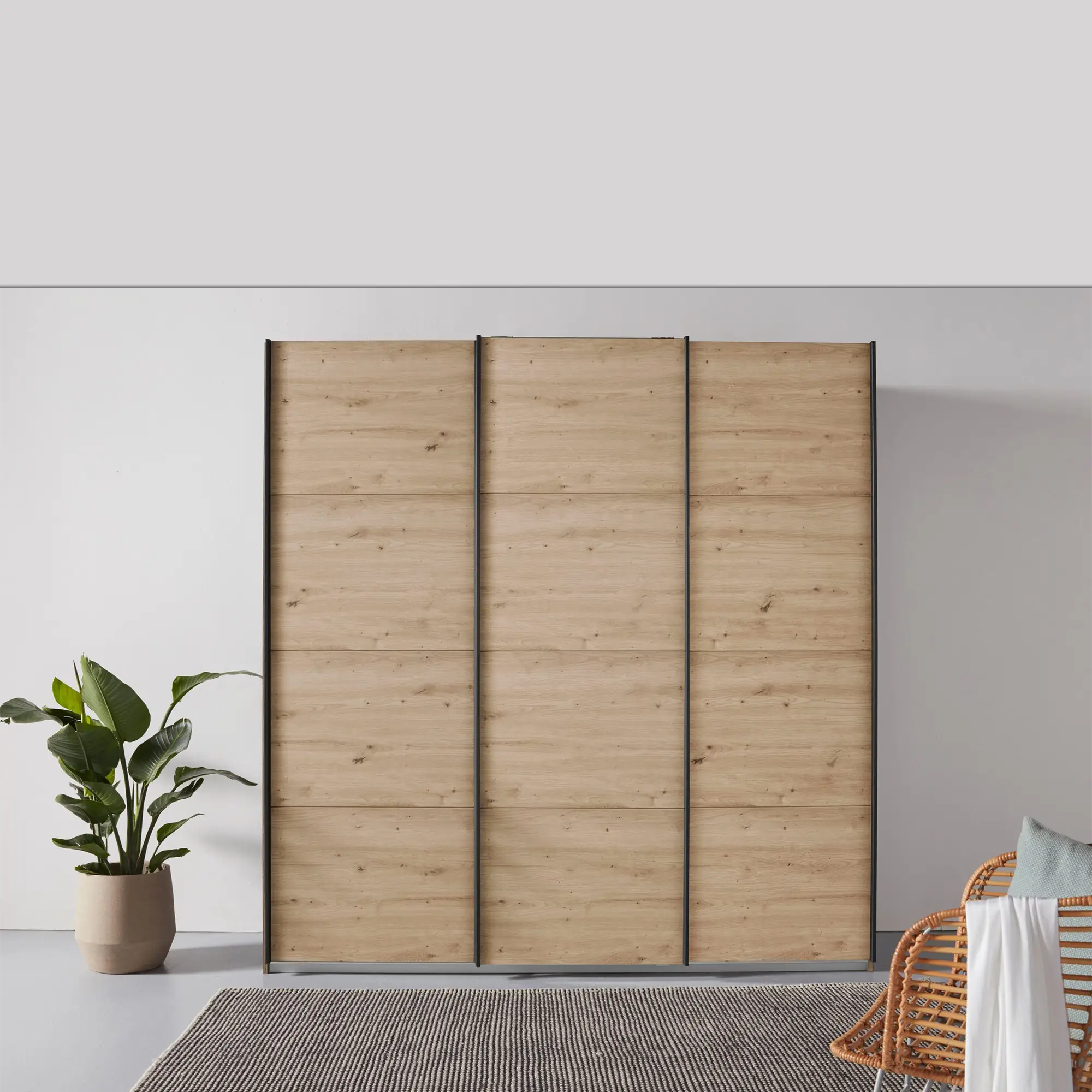 Pendle Village Furniture presents Rauch Forms 3 Door Sliding Wardrobe in Warm Oak with Metallic Grey Handles. Three internal compartments offer ample storage. Choose from two height options – 210cm or 229cm. Available in two width sizes: Small (203cm) and Large (271cm). Enjoy the convenience of Free Assembly - Lifestyle Image